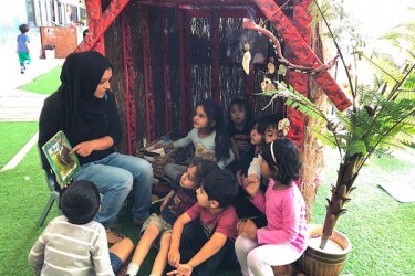 Children and teacher reading in a multicultural class. 