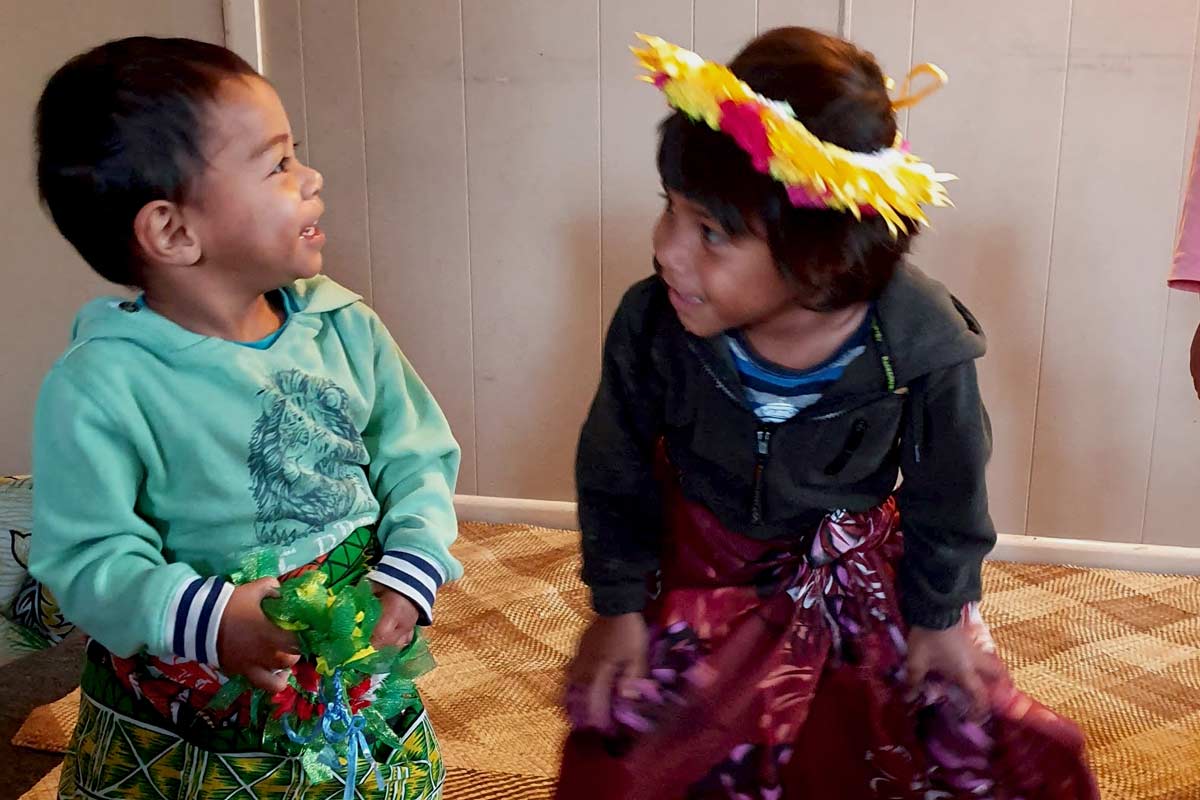 Two children dressed up and dancing on a mat in their room.