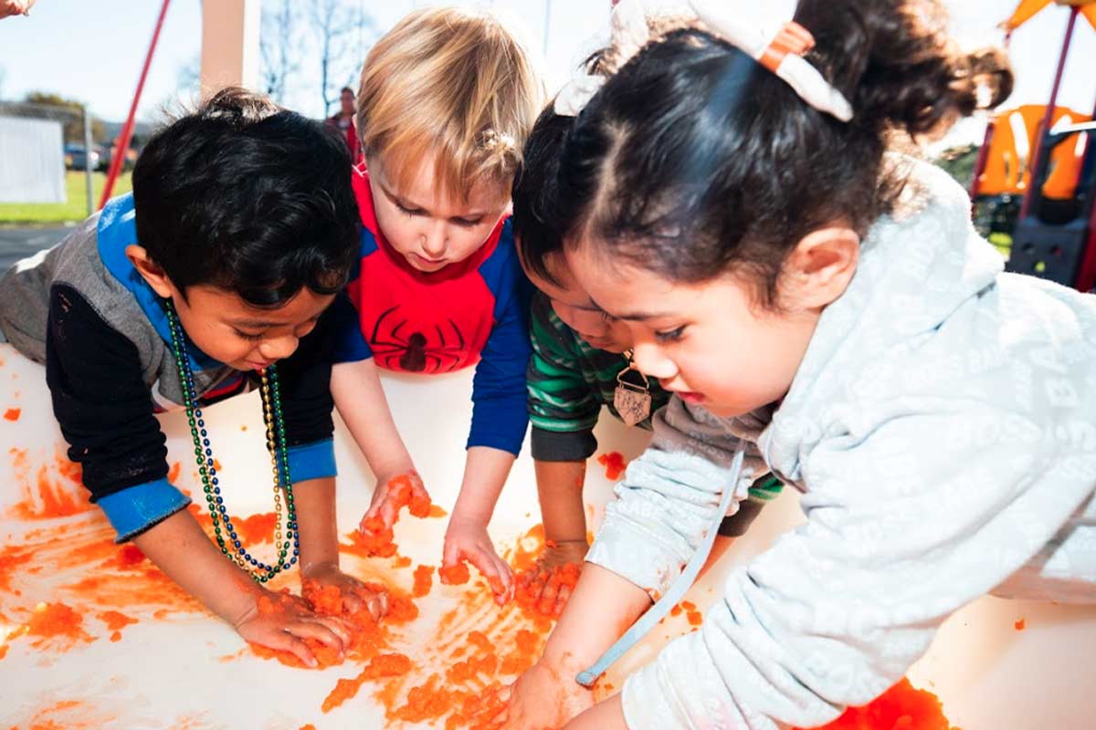 A group of children playing with orange coloured slime.