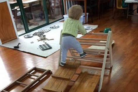 A toddler climbing on wooden equipment.