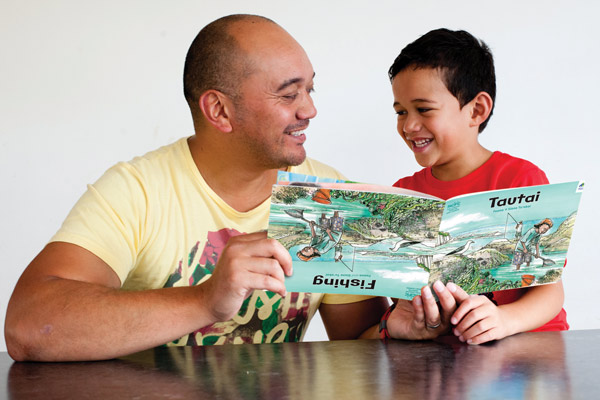 Father and son reading a book together in their own language.