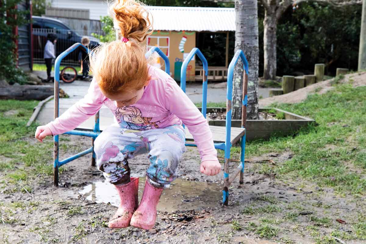 Child jumping in a mud puddle.