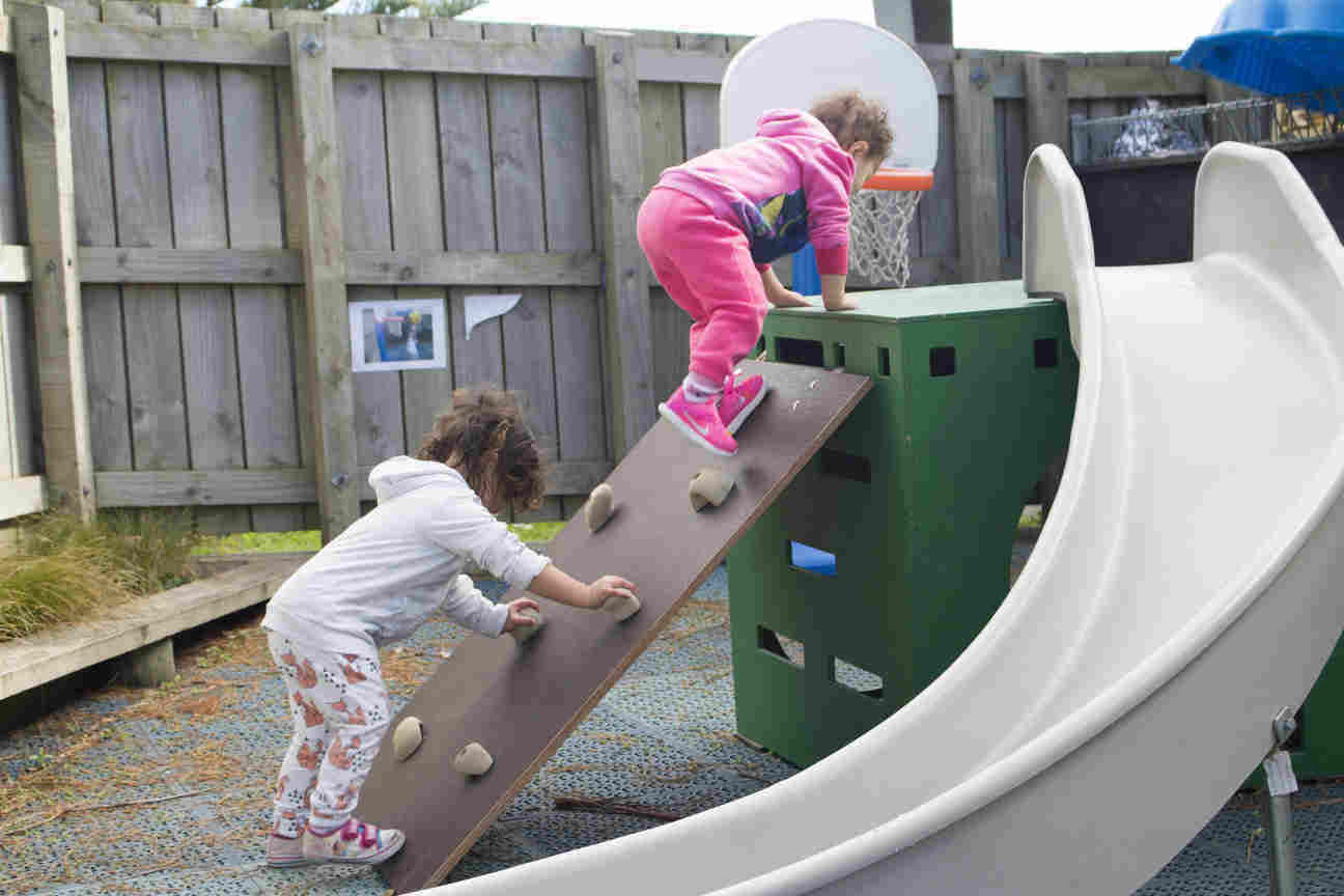 Two children playing on a slide. 